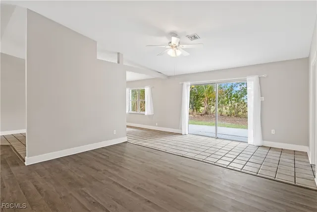 a view of an empty room with a window and wooden floor
