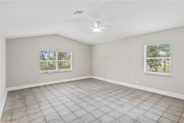 an empty room with windows and ceiling fan