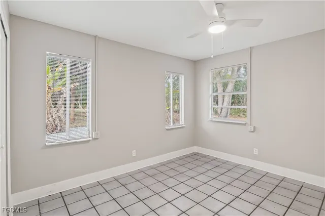 an empty room with windows and fan