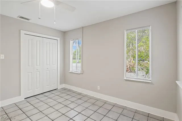 a view of an empty room with window and cabinet area