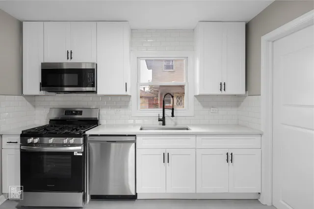 a kitchen with white cabinets and stainless steel appliances