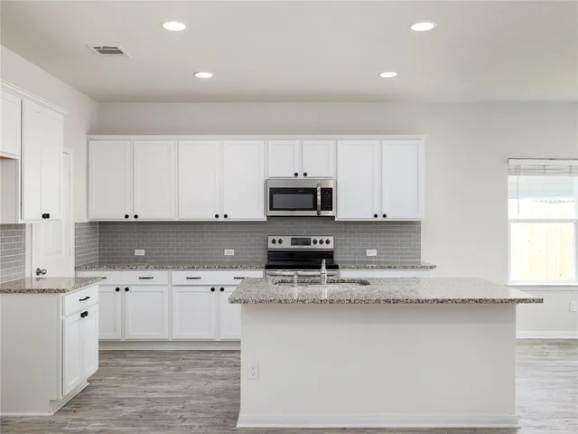 a kitchen with granite countertop a sink a stove and cabinets