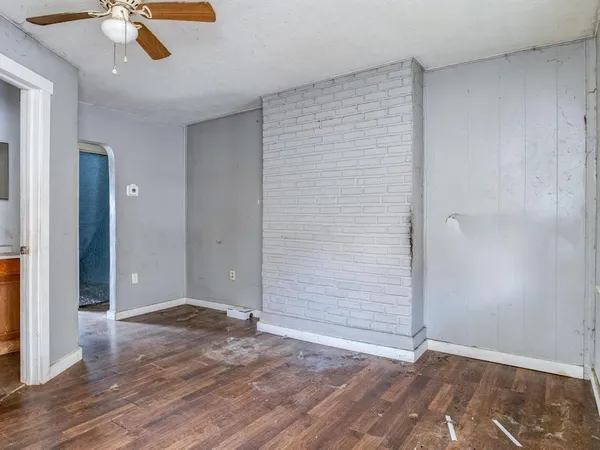an empty room with wooden floor fan and window