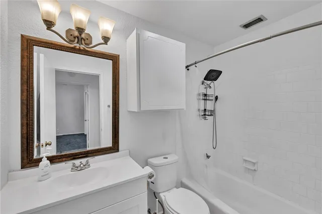 a bedroom with a bed a painting on the wall and a potted plant