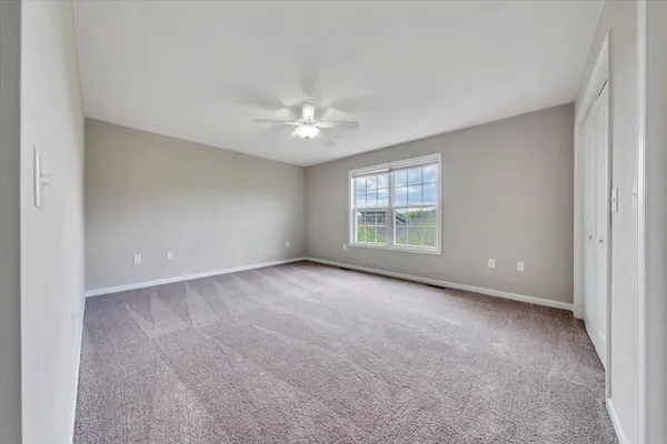 an empty room with windows and ceiling fan
