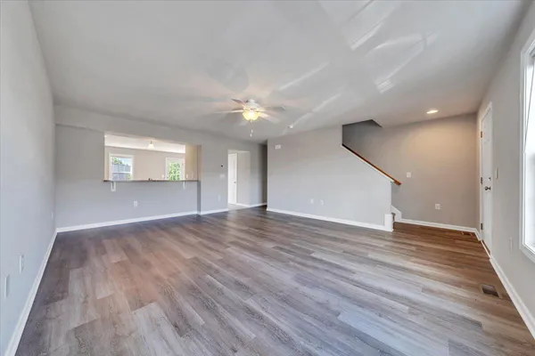 a view of an empty room with wooden floor and a window