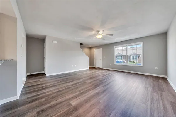 an empty room with wooden floor chandelier and windows