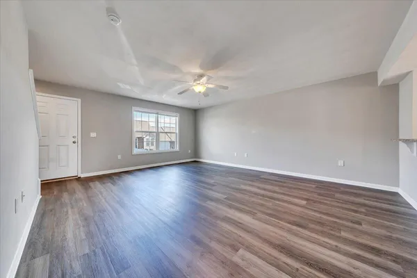 a view of an empty room with window and wooden floor