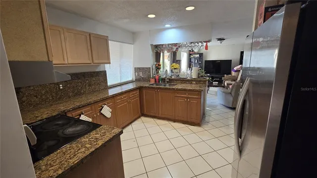 a kitchen with stainless steel appliances granite countertop a sink stove refrigerator and cabinets