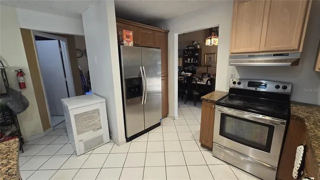 a kitchen with granite countertop a refrigerator and a stove top oven