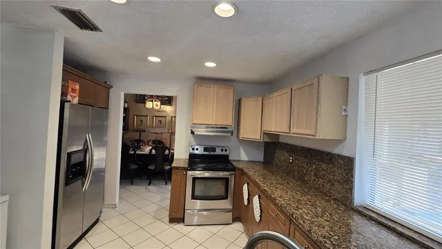 a kitchen with stainless steel appliances granite countertop a refrigerator a stove and a sink