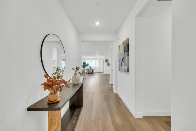 a kitchen with stainless steel appliances kitchen island granite countertop a stove a sink a refrigerator and white cabinets with wooden floor