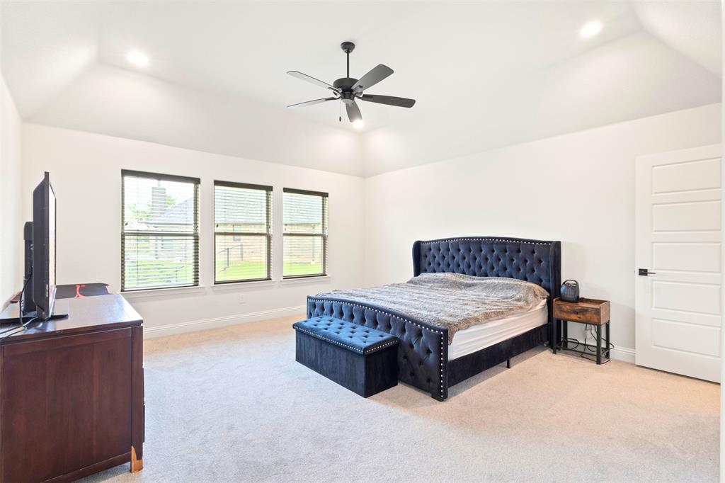 105 Clayton Crossing Springtown, TX 76082 - Photo 13 of 40 a spacious bedroom with a bed and a flat tv screen on dresser