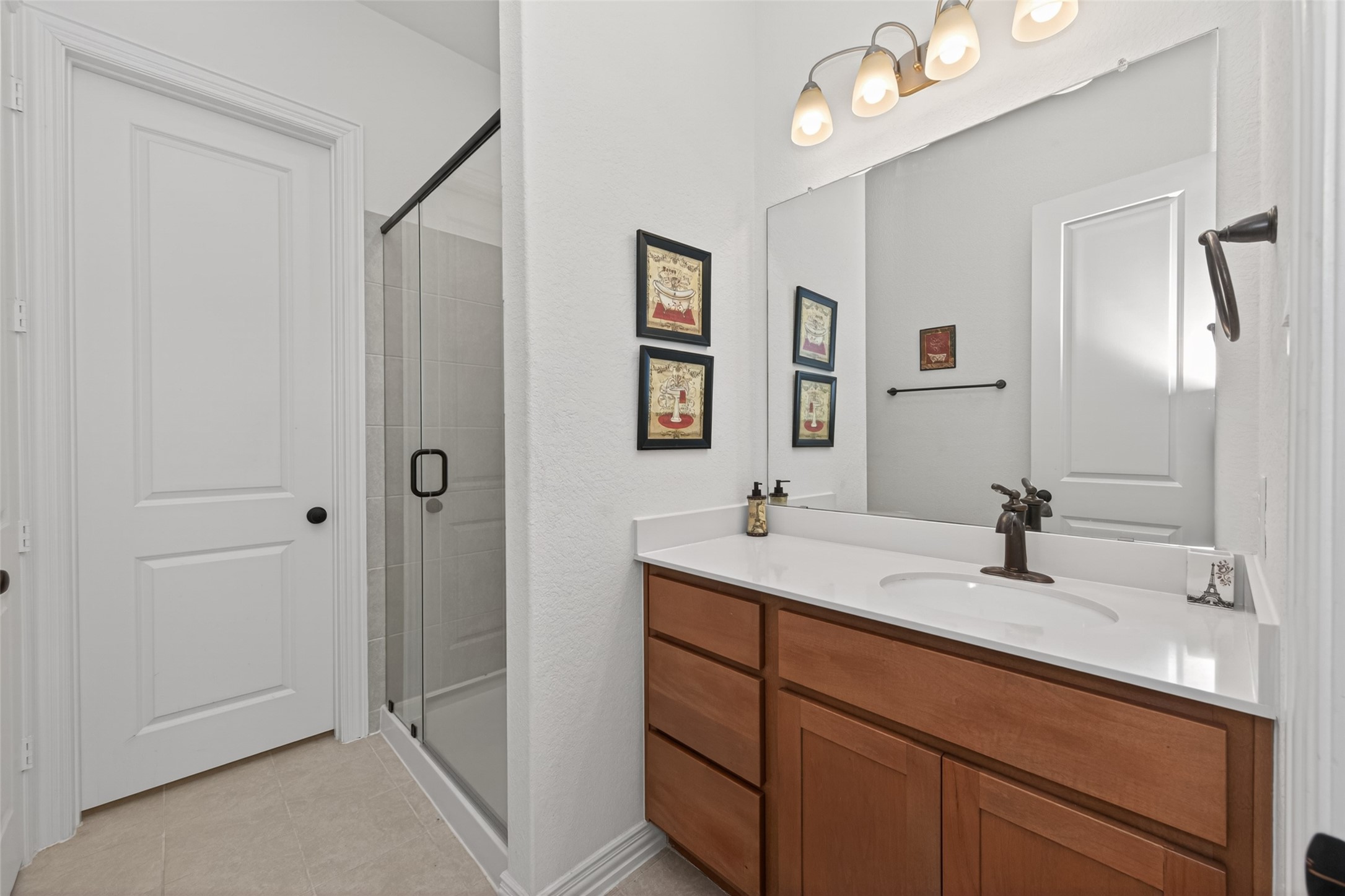20802 Mirror Point Drive Cypress, TX 77433 - Photo 27 of 37 This bathroom features a sleek design with a glass-enclosed shower, contemporary fixtures, and a large mirror above a spacious vanity. Neutral tile work and ample lighting create a clean and inviting ambiance.