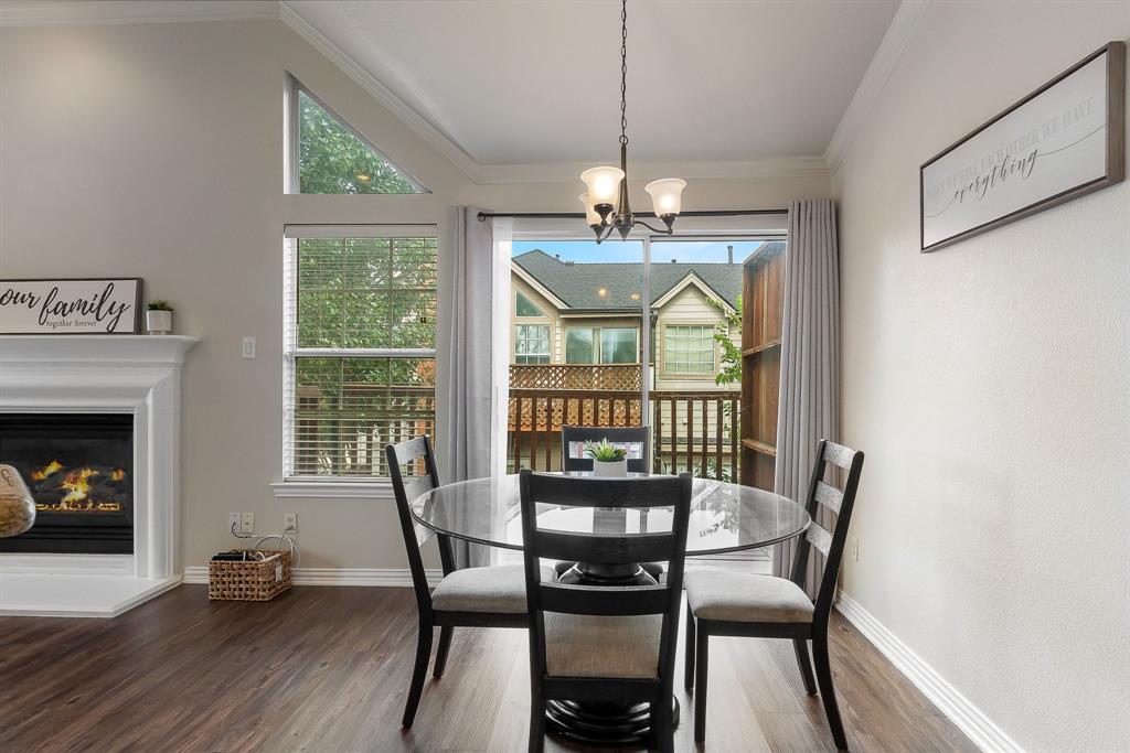 18240 Midway Road, Unit 1301 Dallas, TX 75287 - Photo 10 of 25 Dining area with wood-finish flooring, a fireplace featuring a white mantel, and vaulted ceilings with a triangular window