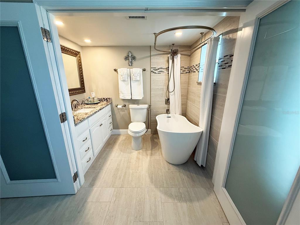 4455 Duhme Road, Unit 103 St. Petersburg, FL 33708 - Photo 18 of 37 a large spacious bathroom with a granite countertop tub sink a mirror a vanity and a shower