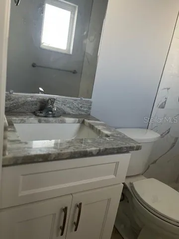 a bathroom with a granite countertop toilet and a sink