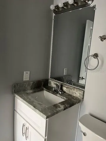 a bathroom with a granite countertop sink and a mirror