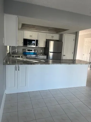 a kitchen with stainless steel appliances a sink a stove a microwave a counter top space and cabinets