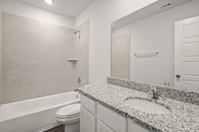 a bathroom with a granite countertop sink a toilet and shower
