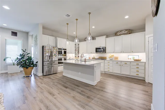 a kitchen with stainless steel appliances kitchen island wooden floors and white cabinets