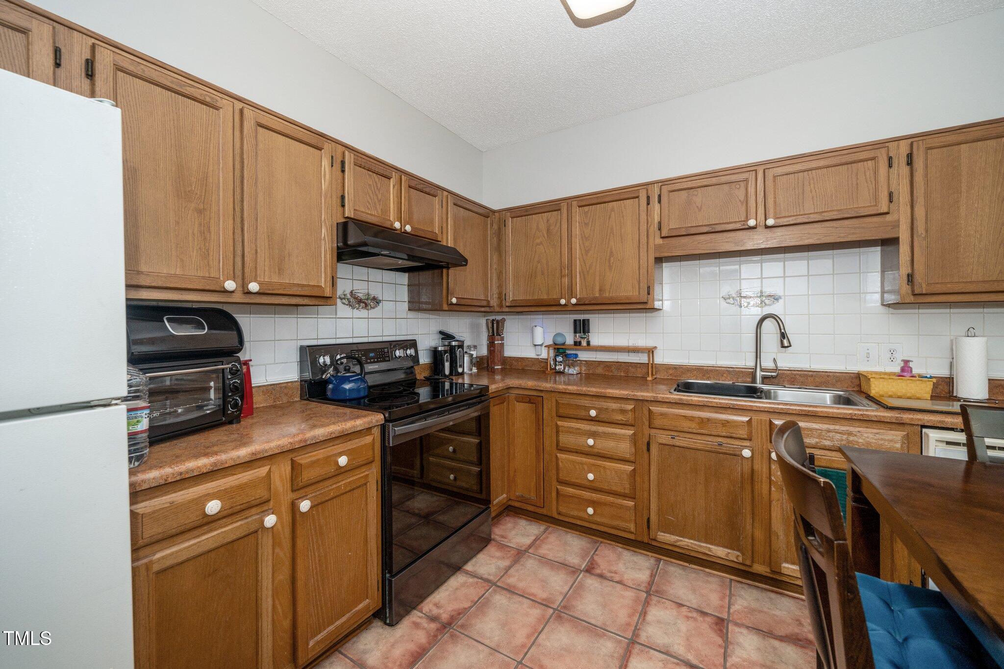 6008 River Lake Circle Raleigh, NC 27604 - Photo 4 of 25 a kitchen with stainless steel appliances granite countertop a stove top oven a sink dishwasher and cabinets with wooden floor