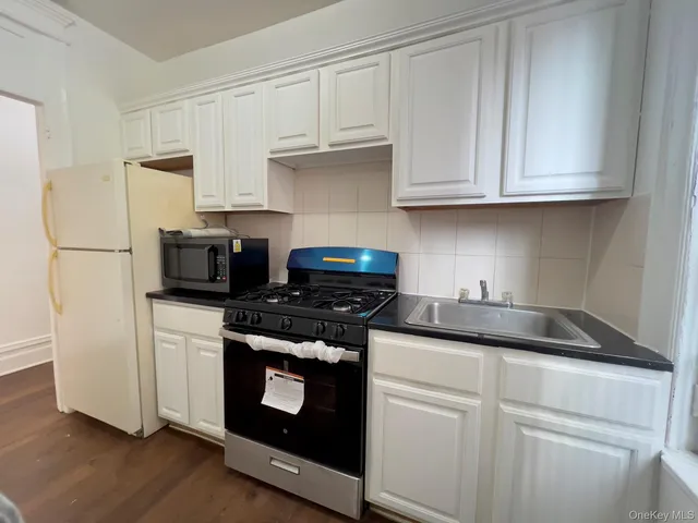a kitchen with granite countertop white cabinets and white appliances