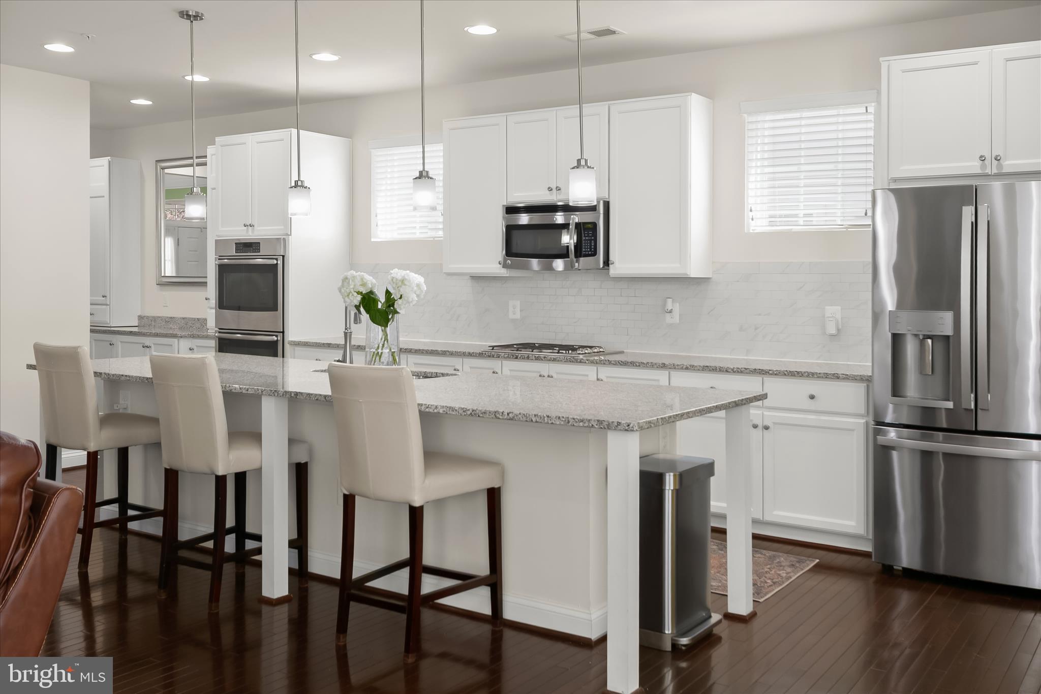 13502 Windy Meadow Lane Silver Spring, MD 20906 - Photo 25 of 74 a kitchen with stainless steel appliances kitchen island granite countertop a table chairs refrigerator and microwave