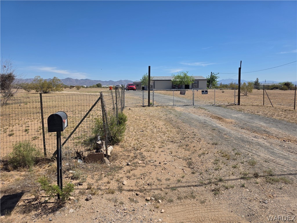 4182 Canelo Road Golden Valley, AZ 86413 - Photo 9 of 31 The property features a fenced perimeter, a gravel driveway, and a gated entrance leading to the residence