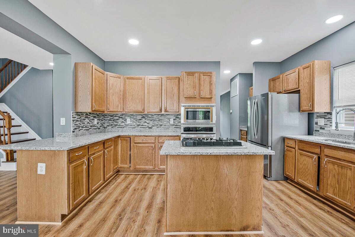 1329 Canberra Drive Baltimore, MD 21221 - Photo 12 of 43 a kitchen with stainless steel appliances granite countertop a stove a sink dishwasher a refrigerator and white cabinets with wooden floor