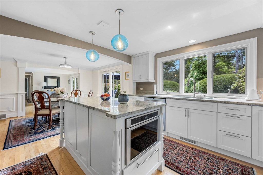 56 Riverview Drive Chatham, MA 02633 - Photo 16 of 37 a kitchen with granite countertop a stove a sink a dining table and chairs with wooden floor