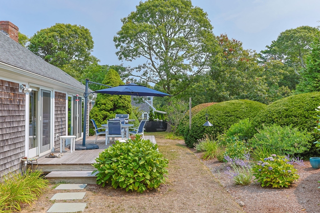 56 Riverview Drive Chatham, MA 02633 - Photo 30 of 37 a view of a patio with table and chairs potted plants and large tree