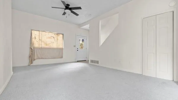 an empty room with windows and ceiling fan