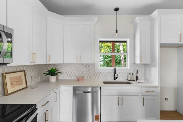 a kitchen with stainless steel appliances white cabinets a table and a window