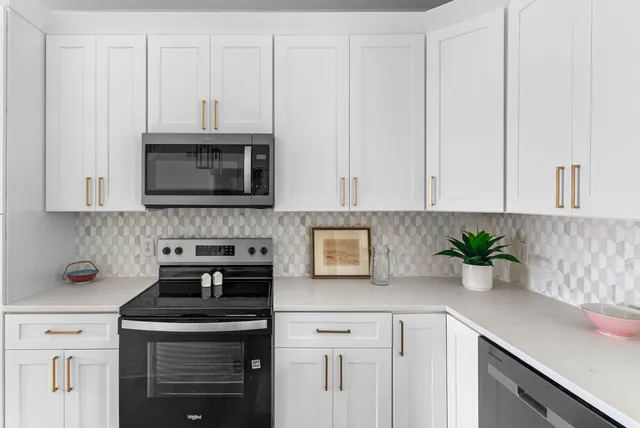 a kitchen with stainless steel appliances white cabinets and a stove top oven