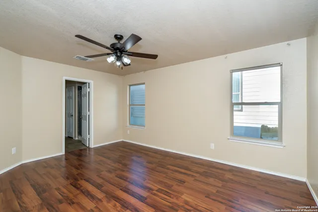 a view of an empty room with window and wooden floor