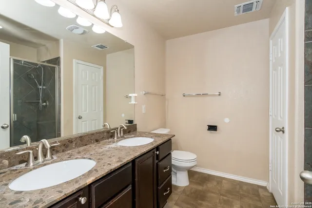 a bathroom with a granite countertop sink a toilet a mirror and shower