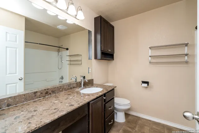 a bathroom with a granite countertop sink a toilet and a mirror