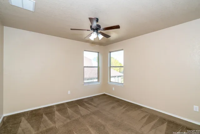 an empty room with windows and fan