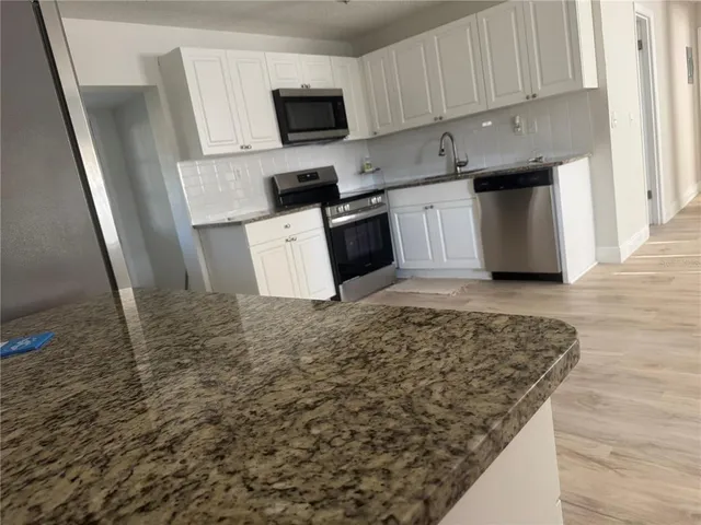 a kitchen with stainless steel appliances wooden floors and wooden cabinets
