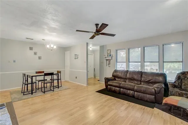 a living room with furniture a ceiling fan and a large window