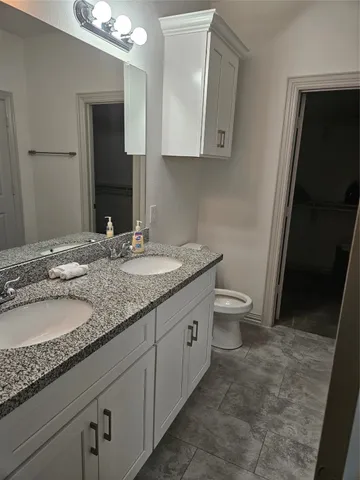 a bathroom with a granite countertop sink a toilet and a mirror
