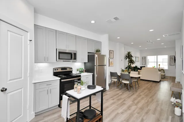 a kitchen with a refrigerator a stove top oven a sink dishwasher and white cabinets with wooden floor