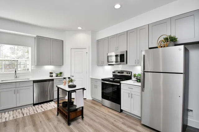 a kitchen with a refrigerator a stove a sink cabinets and wooden floor