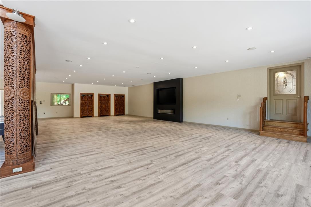 6271 Batman Road Zionsville, PA 18092 - Photo 7 of 100 A spacious recreation room features light-toned plank flooring and ample recessed lighting, with an elegant fireplace creating a focal point.