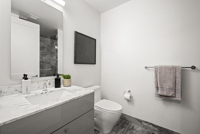 a bathroom with a granite countertop toilet sink and mirror