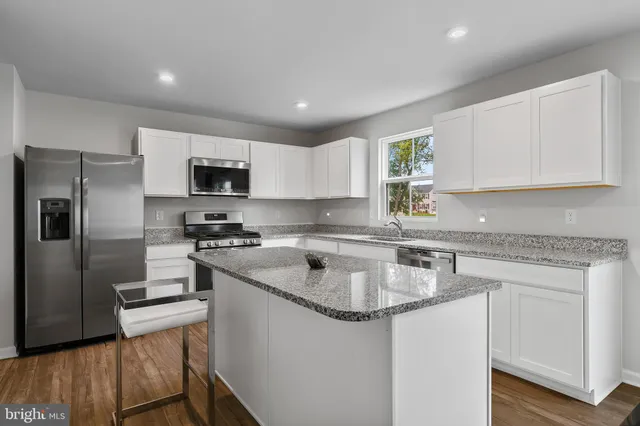 a kitchen with a sink a stove a refrigerator a center island and a window