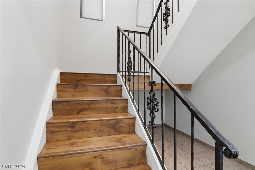 2274 East Desert Inn Road Las Vegas, NV 89169 - Photo 17 of 41 Hardwood stairs ascend to the next level, complemented by an ornate black wrought-iron railing.