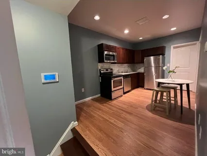 a kitchen with stainless steel appliances granite countertop a refrigerator and a stove top oven with wooden floor