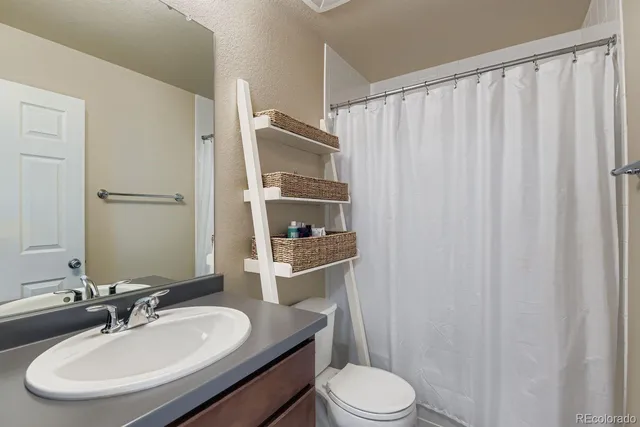a bathroom with a sink a toilet a mirror and shower curtain